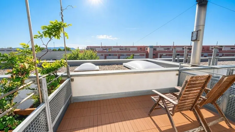 Sonnige Dachterrasse mit Holzdeck und bequemen Liegestühlen, ideal zum Entspannen mit Weitblick.