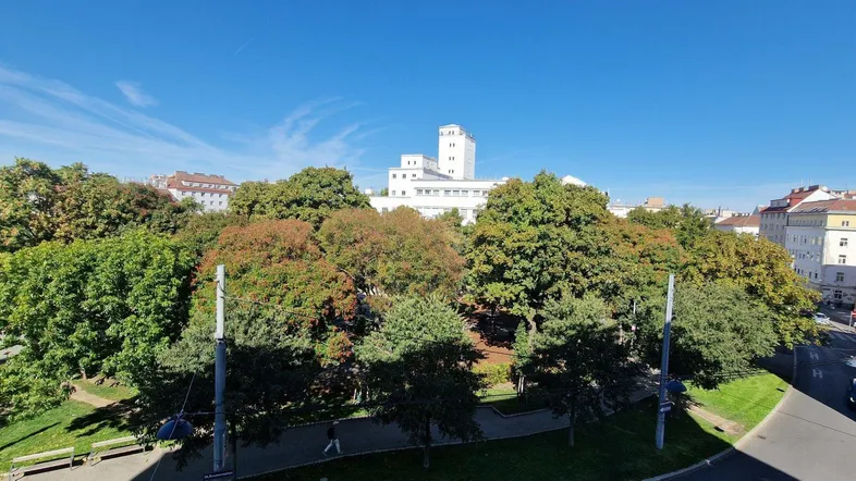 Panoramablick über grüne Bäume auf städtische Gebäude unter blauem Himmel.