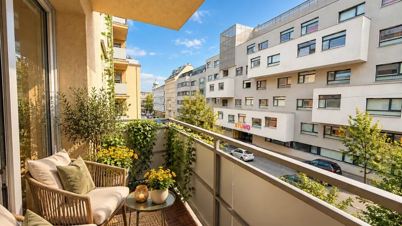 Möblierter Balkon mit Holzboden und Blick auf die Stadt, ideal zum Entspannen im Freien.