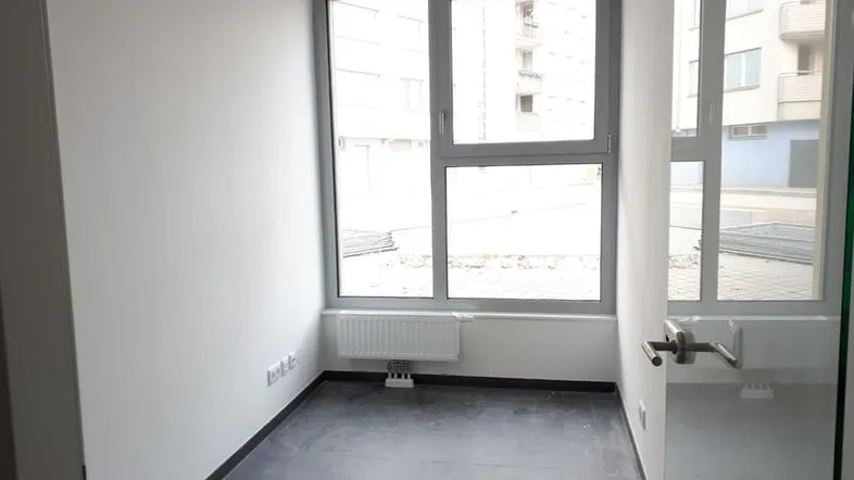 Leerer Raum mit großen Fenstern, die viel Tageslicht hereinlassen und einen Blick nach draußen bieten.