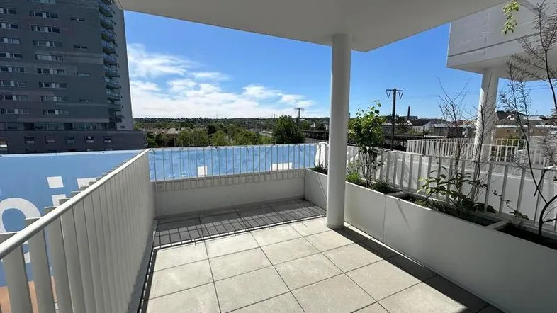 Geräumige Terrasse mit Fliesenboden, modernen Pflanzgefäßen und weitem Blick über die Stadt.