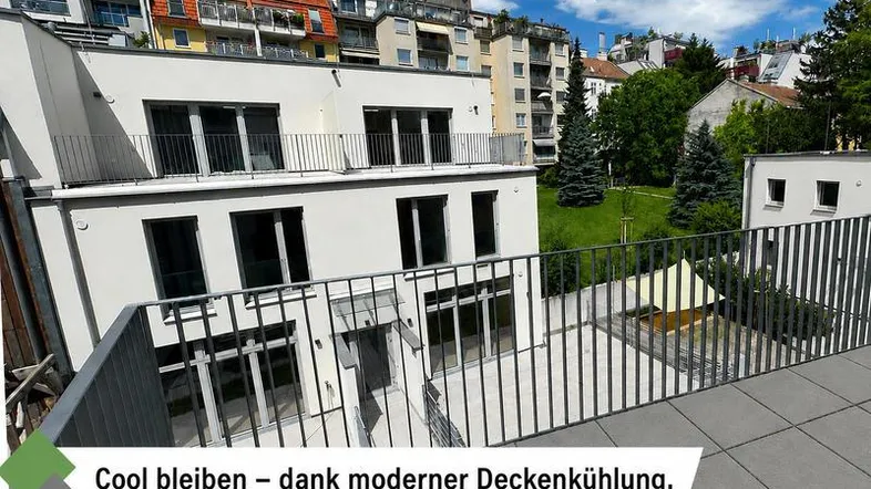 Blick von einer modernen Terrasse auf ein Gebäude mit Balkonen und Grünflächen.