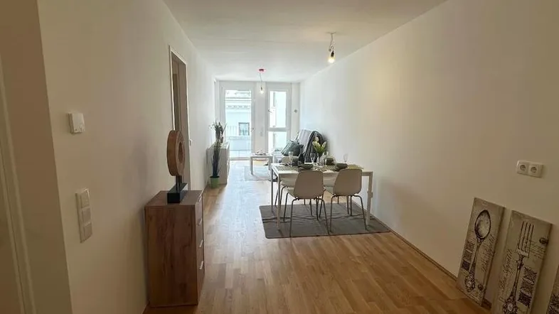 Heller, offener Wohn- und Essbereich mit Parkettboden und Zugang zu einem Balkon.