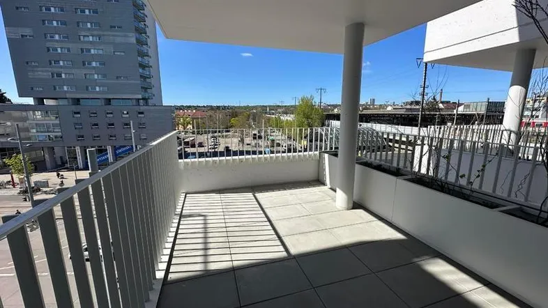 Geräumiger Balkon mit Fliesenboden und Blick auf die Stadt und umliegende Gebäude.
