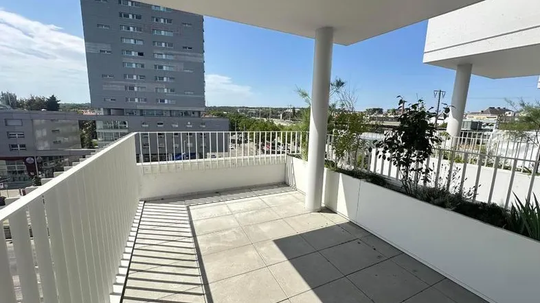 Geräumiger Balkon mit Fliesenboden, weißen Geländern und Blick auf die Stadt.