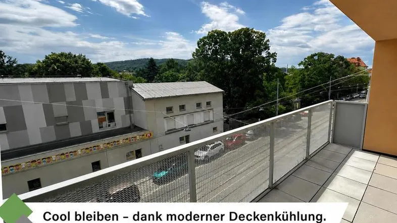 Geräumiger Balkon mit Fliesenboden und Metallgeländer, bietet einen Blick ins Grüne.