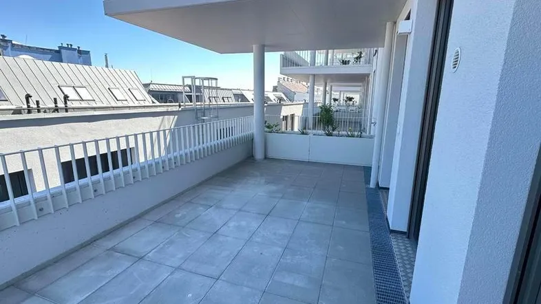 Geräumige Terrasse mit Fliesenboden und Blick auf die umliegenden Gebäude und den Himmel.