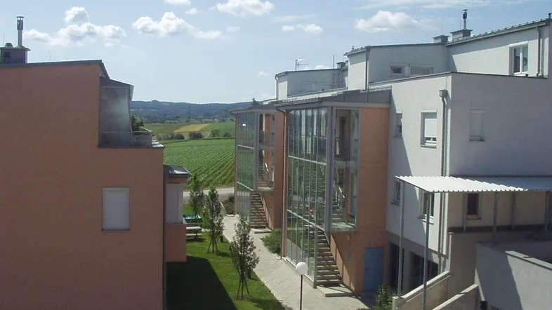 Wohngebäude mit verglasten Treppenhäusern, einem grünen Innenhof und Blick auf die umliegende Landschaft.