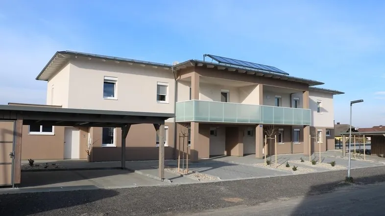 Neubau-Wohngebäude mit modernen Balkonen, Carports und Photovoltaikanlage auf dem Dach.