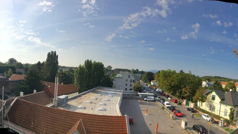 Panoramablick über Dächer, Bäume und eine städtische Umgebung mit einer Baustelle in der Ferne.