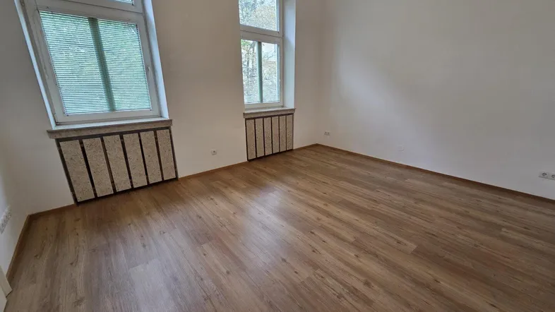 Helles Zimmer mit Laminatboden und zwei Fenstern, ideal als Wohn- oder Schlafbereich.
