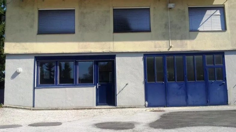 Fassade eines Gebäudes mit Solarpaneelen auf dem Dach und blauen Türen und Fenstern.