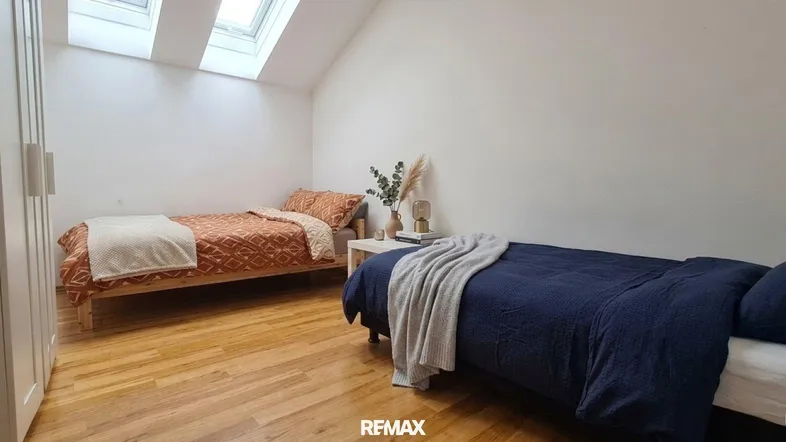 Helles Schlafzimmer im Dachgeschoss mit zwei Betten, Holzboden und Dachfenstern, die viel Licht spenden.
