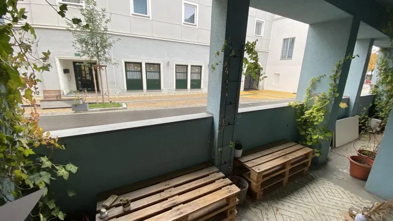 Gemütliche Loggia mit selbstgebauten Palettenmöbeln und Blick auf den Innenhof.