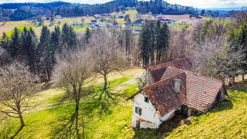 Luftaufnahme eines ländlichen Anwesens mit mehreren Gebäuden und weitläufigen grünen Hügeln.