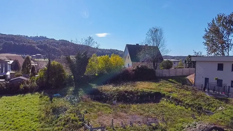 Weitläufiges Grundstück mit Blick auf die umliegende Hügellandschaft und benachbarte Häuser.