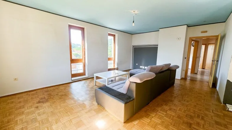 Helles Wohnzimmer mit Parkettboden, beiger Couch und hellblauer Decke, bereit zur individuellen Gestaltung.