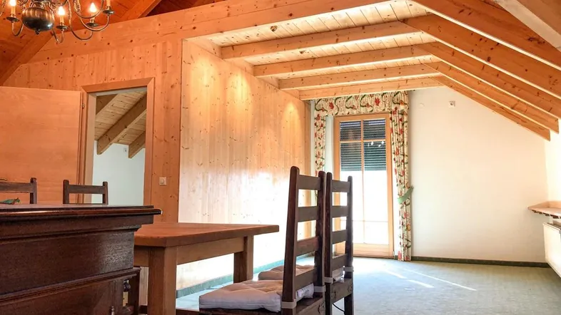 Gemütlicher Essbereich im Dachgeschoss mit sichtbaren Holzbalken und traditioneller Einrichtung.