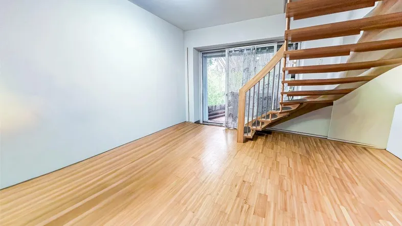 Heller Wohnbereich mit Holztreppe, Parkettboden und Schiebetür zum Außenbereich.