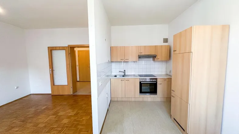 Küche mit hellen Holzfronten und Parkettboden im angrenzenden Wohnbereich.