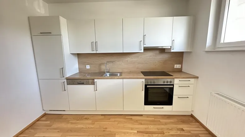 Moderne Einbauküche mit weißen Hochglanzfronten, Holzoptik-Arbeitsplatte und integrierten Geräten.