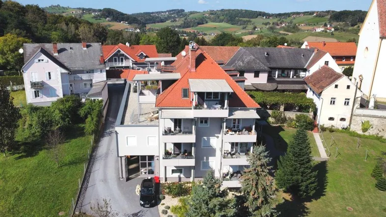 Luftaufnahme eines modernen Wohngebäudes mit Balkonen und umliegender grüner Landschaft.