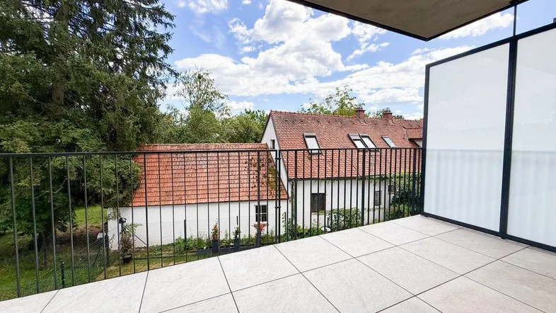 Geräumiger Balkon mit Fliesenboden und Blick auf die umliegende Wohnbebauung und viel Grün.
