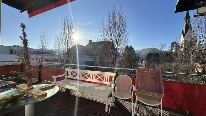 Sonnige Terrasse mit Holzboden und Sitzgelegenheiten, bietet einen weiten Blick auf die Umgebung.