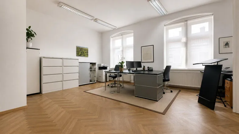 Geräumiges Büro mit zwei Arbeitsplätzen, hellen Wänden und elegantem Fischgrätparkettboden.