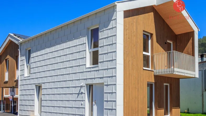 Modernes Einfamilienhaus mit Holz- und Schindelfassade unter blauem Himmel.