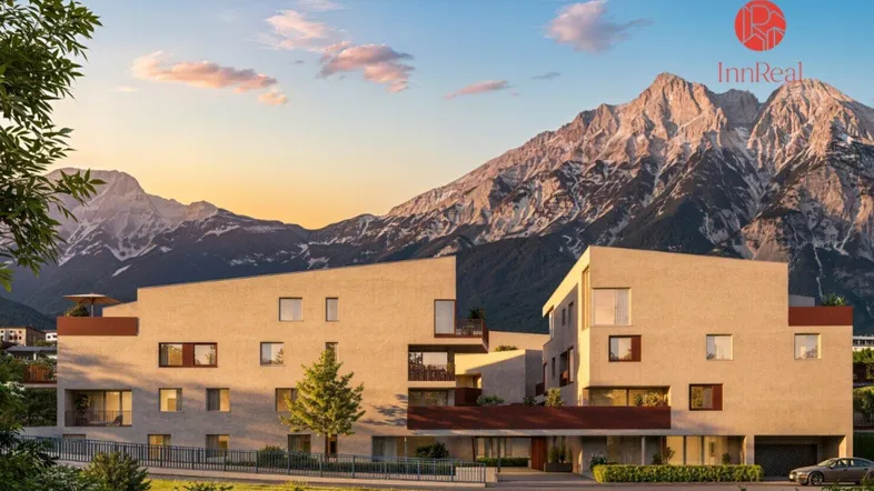 Moderne Wohnanlage mit klarer Architektur und beeindruckendem Bergblick bei Sonnenuntergang.