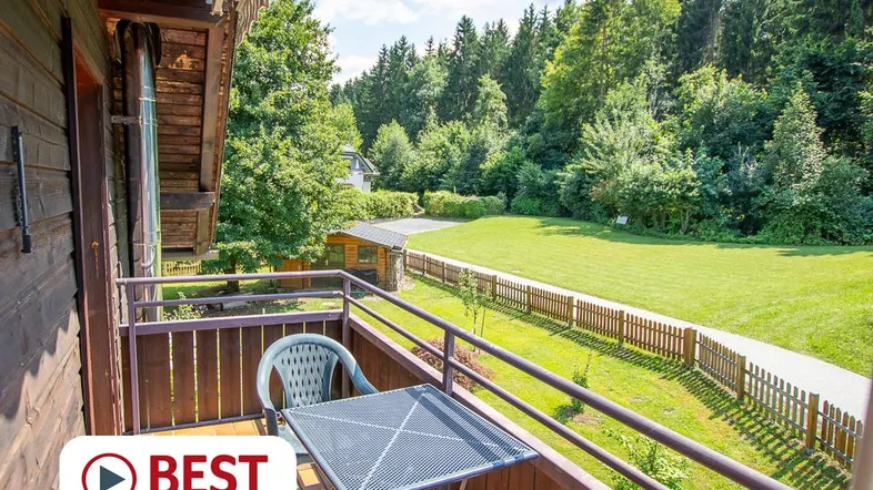 Balkon mit Sitzgelegenheiten und weitem Blick auf die grüne Landschaft und Wälder.