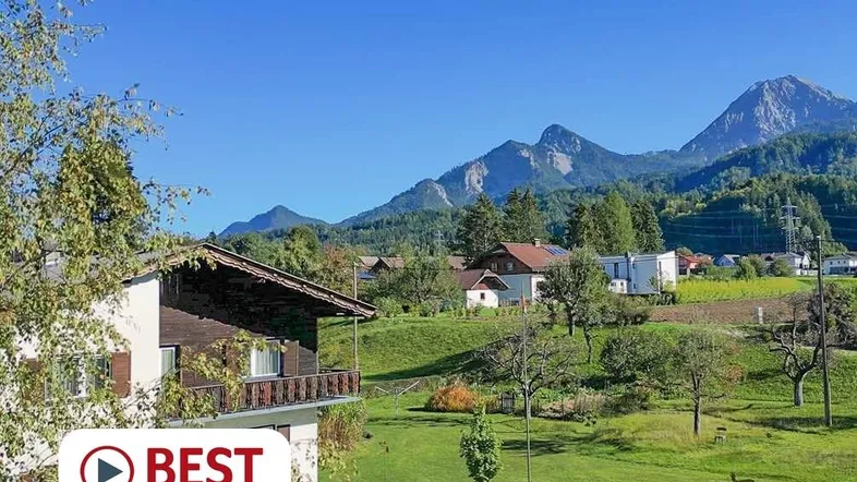Malerisches Haus in alpiner Landschaft mit weitem Blick auf die Berge und grüne Wiesen.