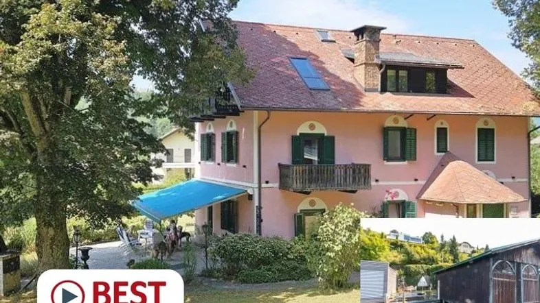 Rosa Villa mit rotem Dach, grünen Fensterläden und einer Terrasse mit blauer Markise und Seeblick.