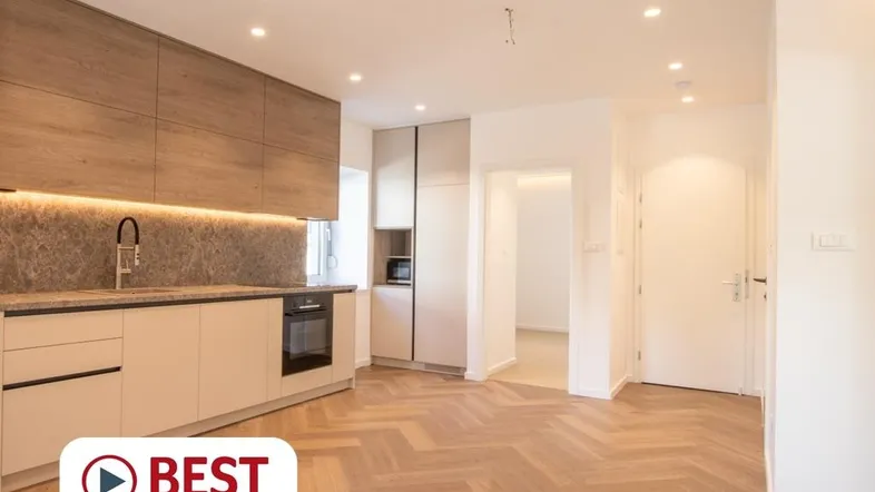 Moderne Einbauküche mit Holzfronten, Steinrückwand und Fischgrätparkett in einem offenen Wohnbereich.