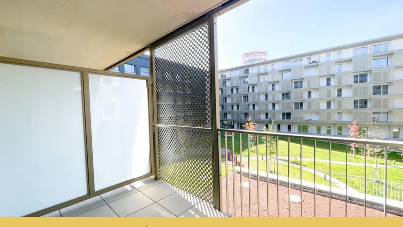 Heller Balkon mit Blick auf den begrünten Innenhof und moderne Wohngebäude.