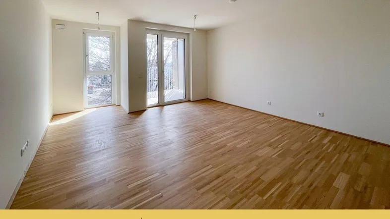 Helles Wohnzimmer mit Parkettboden und Zugang zu einem Balkon, ideal für natürliche Belichtung.