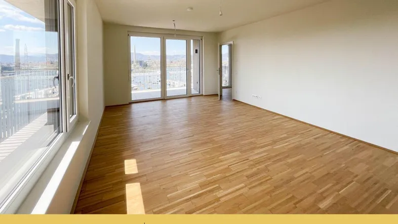 Helles Wohnzimmer mit Parkettboden, großen Fenstern und Zugang zu einem Balkon mit Aussicht.
