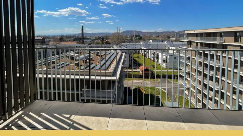 Geräumiger Balkon mit Fliesenboden und weitem Blick über die umliegende Stadtlandschaft und Dächer.