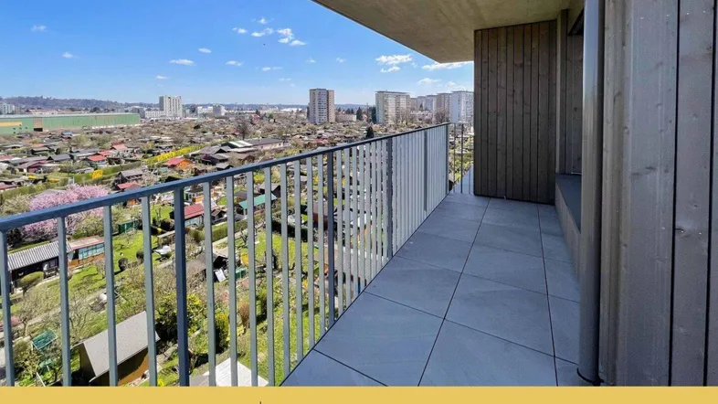 Geräumiger Balkon mit Fliesenboden und weitem Blick über Kleingärten und die Stadt.