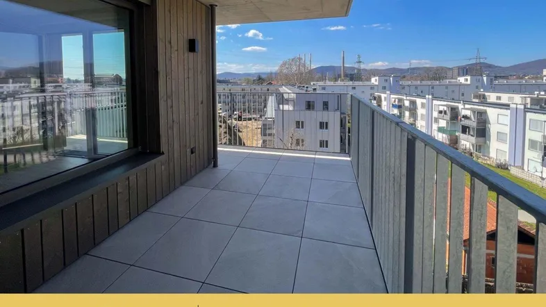 Geräumiger Balkon mit Fliesenboden und Blick auf die umliegende Wohnbebauung und grüne Hügel.