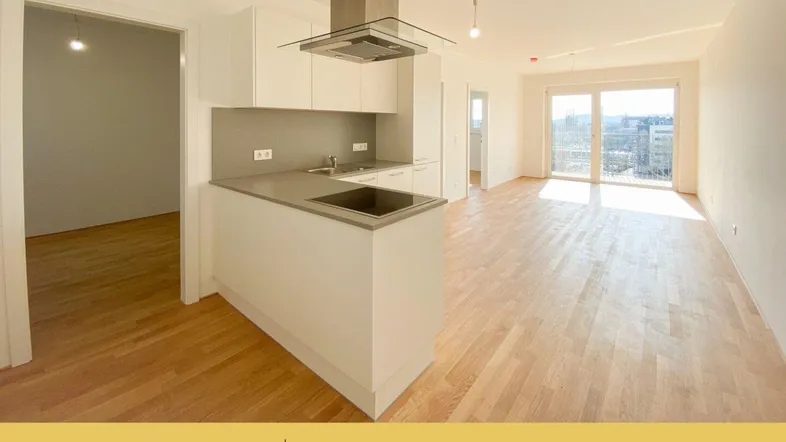 Helles, offenes Wohnzimmer mit integrierter Küche, Parkettboden und Zugang zu großen Fenstern mit Stadtblick.