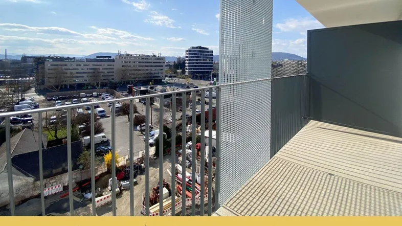Blick vom Balkon auf die Stadt mit umliegenden Gebäuden und einem Parkplatz.