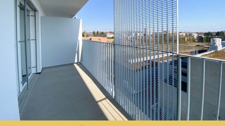 Geräumiger Balkon mit modernem Metallgeländer und weitem Blick unter blauem Himmel.