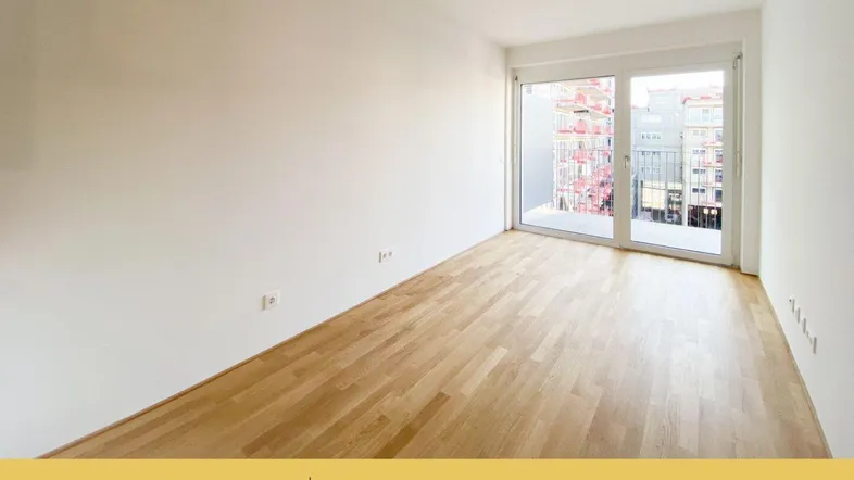 Heller, leerer Wohnraum mit neuem Parkettboden und Zugang zu einem Balkon.
