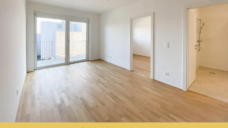 Helles Wohnzimmer mit Parkettboden und Zugang zu einem Balkon, ideal für entspannte Stunden.