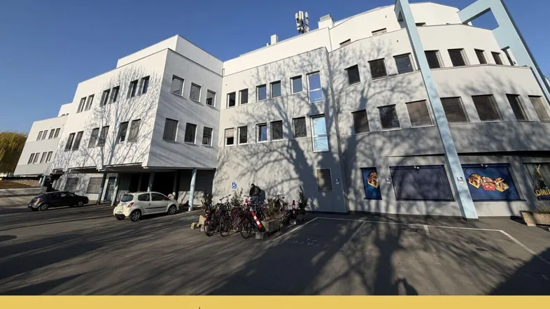 Gesamtansicht des Bürogebäudes mit Parkplätzen und Fahrradständern vor der Fassade.