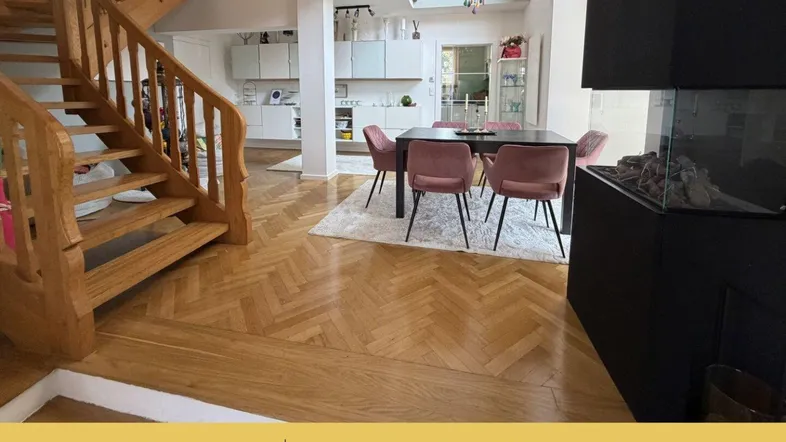 Heller offener Wohn- und Essbereich mit Holztreppe, Parkettboden und modernem Kamin.