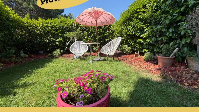 Gepflegter Gartenbereich mit Sitzgelegenheiten und Sonnenschirm, umgeben von grünen Hecken.