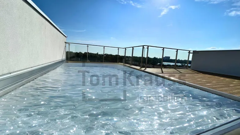 Sonnige Dachterrasse mit kleinem Pool und weitem Blick über die Umgebung und das Wasser.